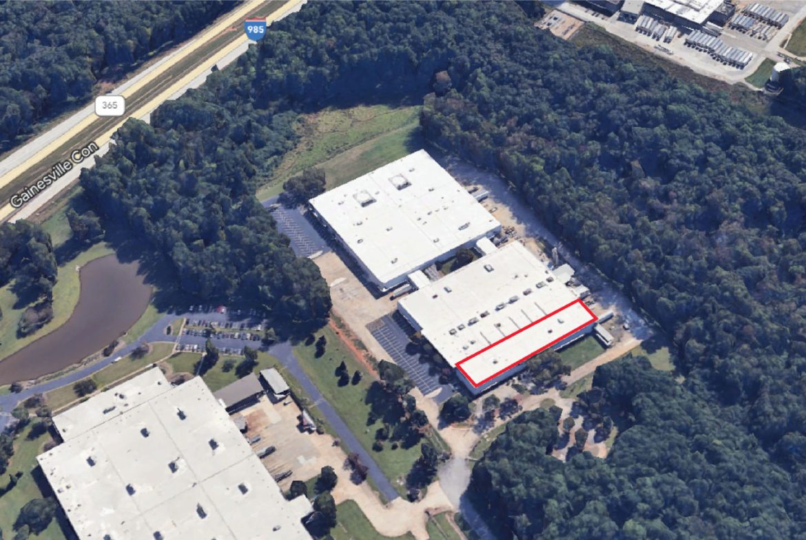 A aerial view of an industrial building with trees in the background.